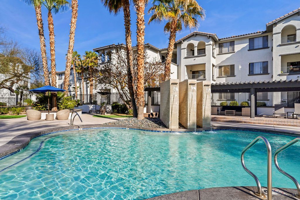 Outdoor pool area at an apartment community with palm trees and lounge seating.
