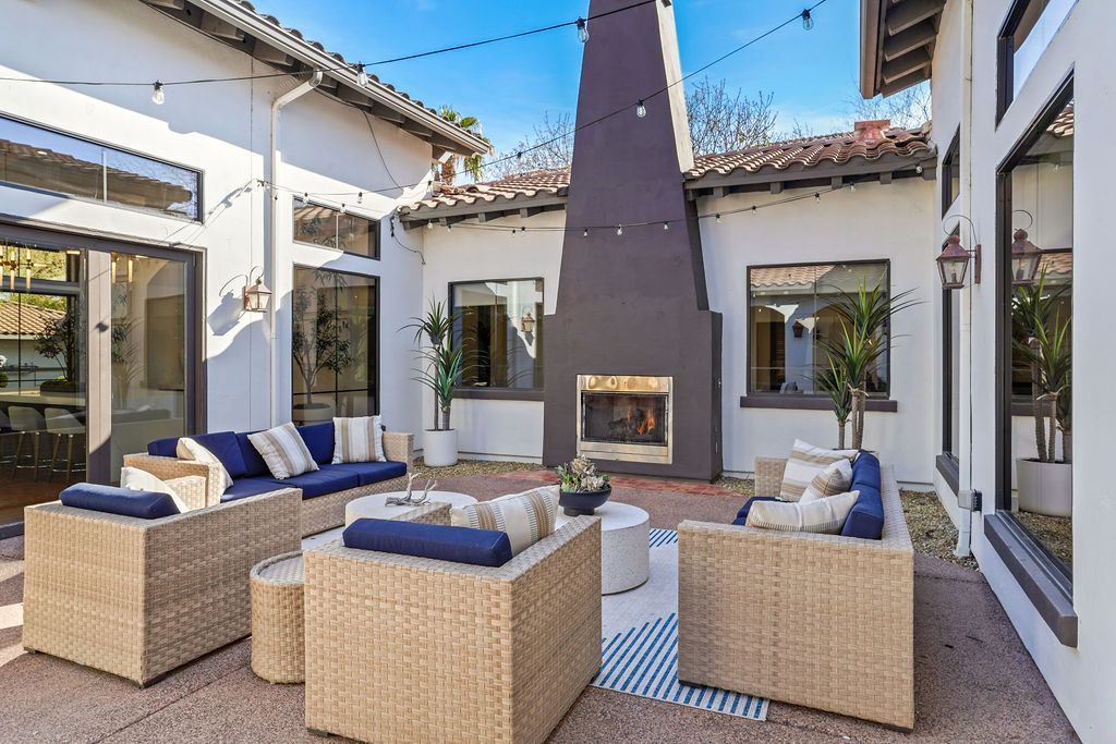 Outdoor communal courtyard with wicker seating and a central fireplace under string lights.