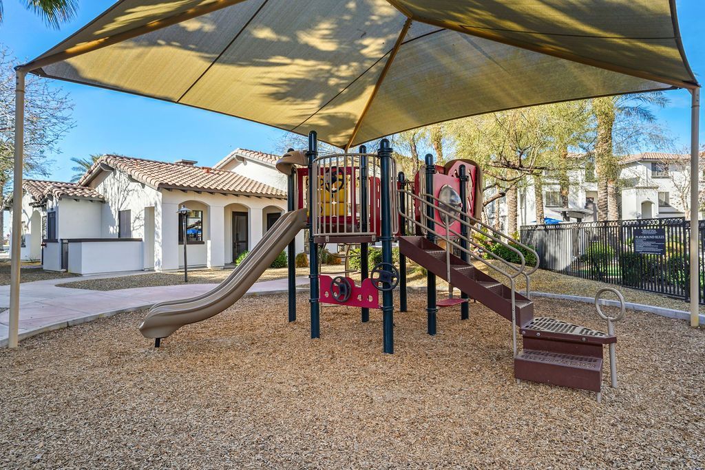 Playground with slides and climbing structure under a shade sail at an apartment complex.
