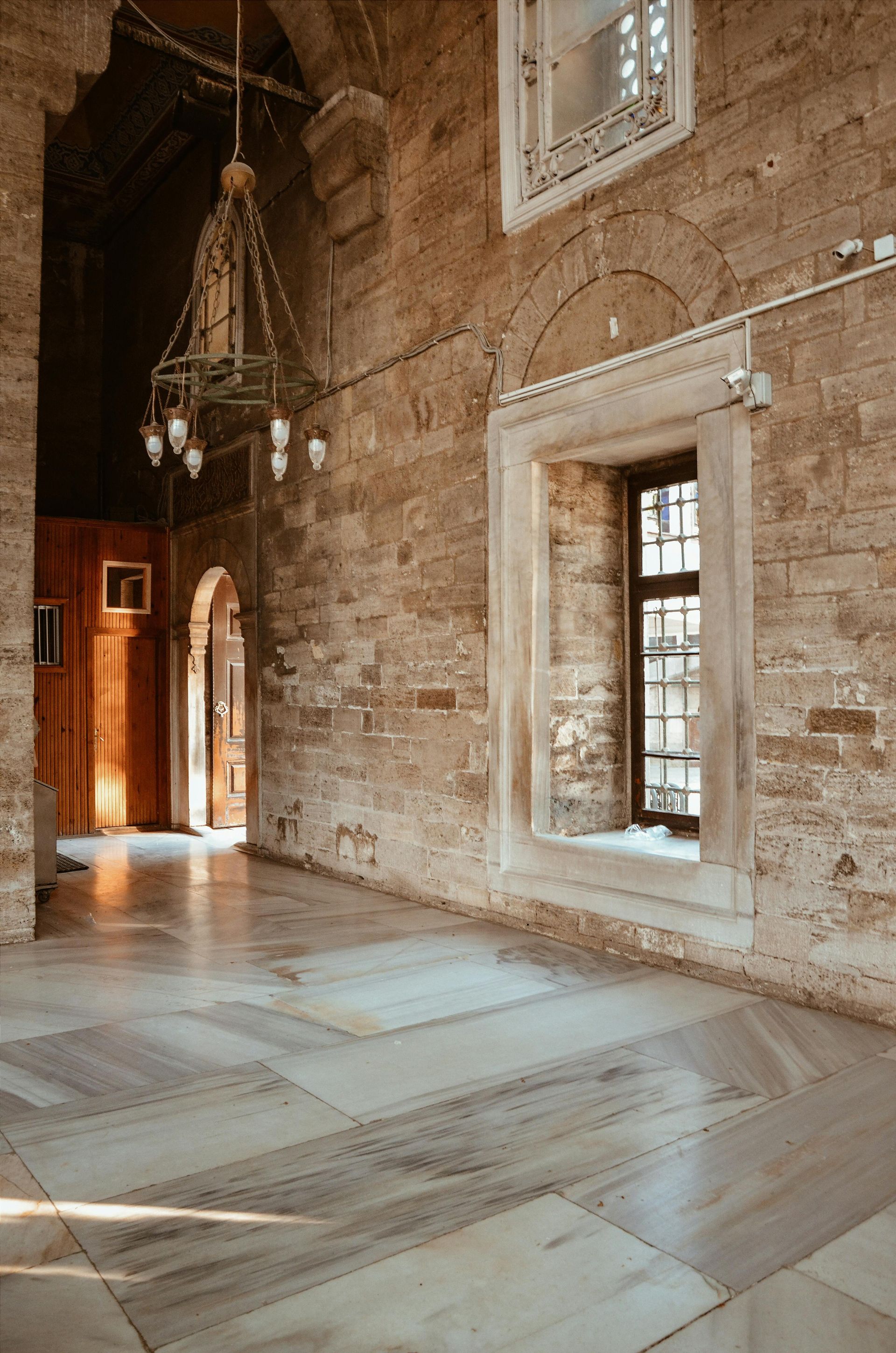 Interior view of a stone building with marble floor and arched doorways. 