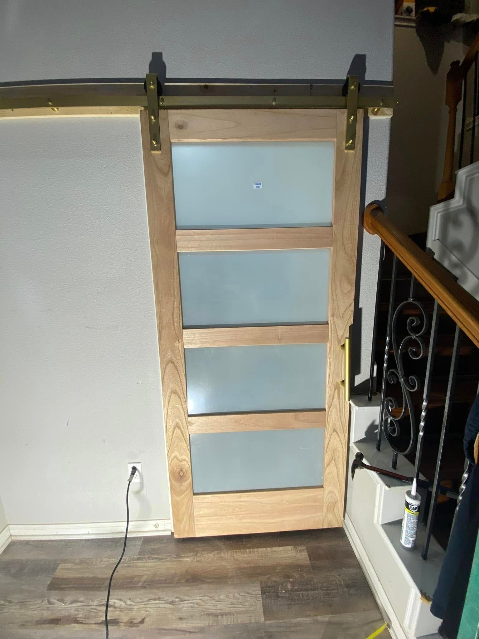 Sliding wood and frosted-glass door, mounted on a brass track, next to a staircase.