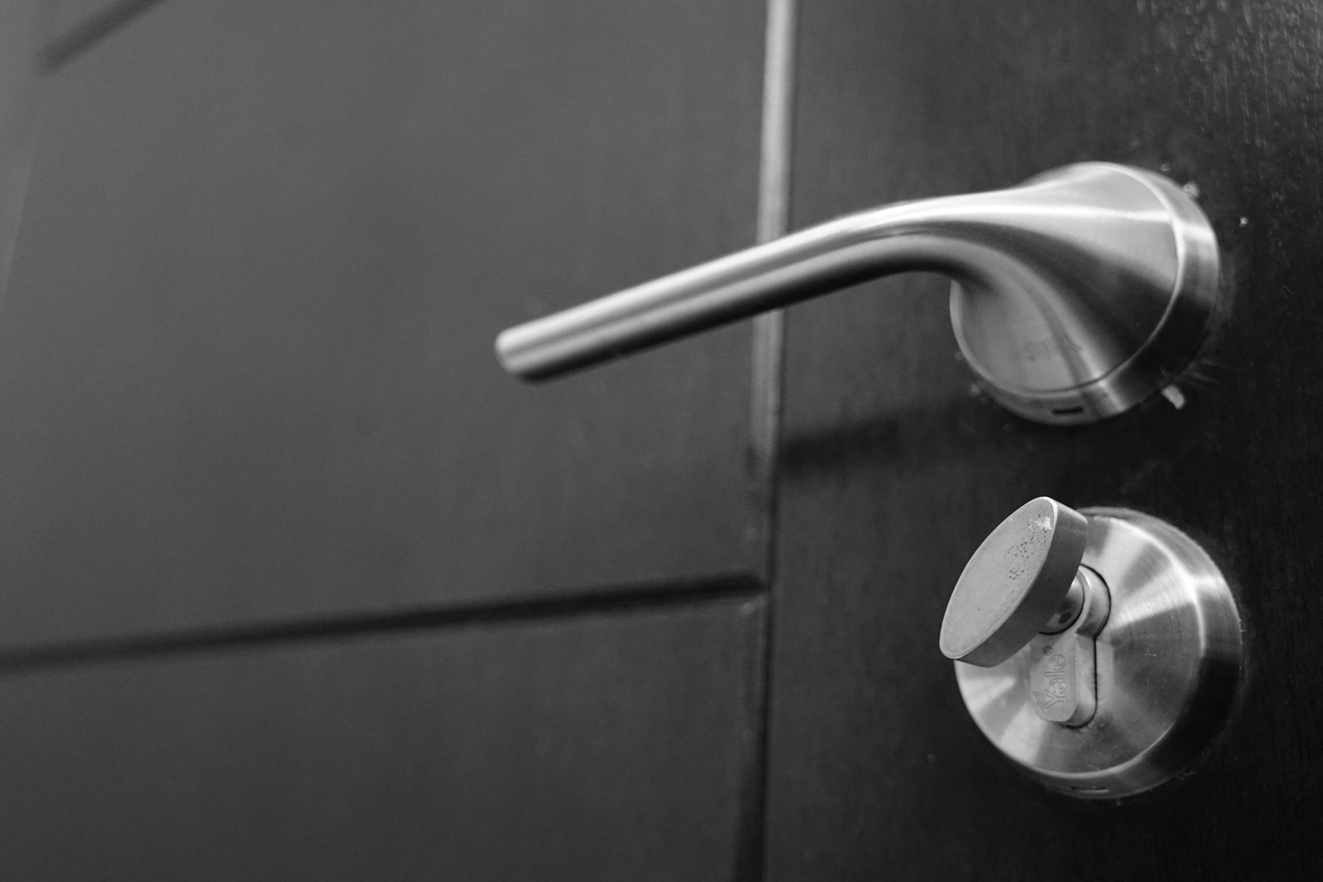 Silver door handle and keyhole on a dark door.