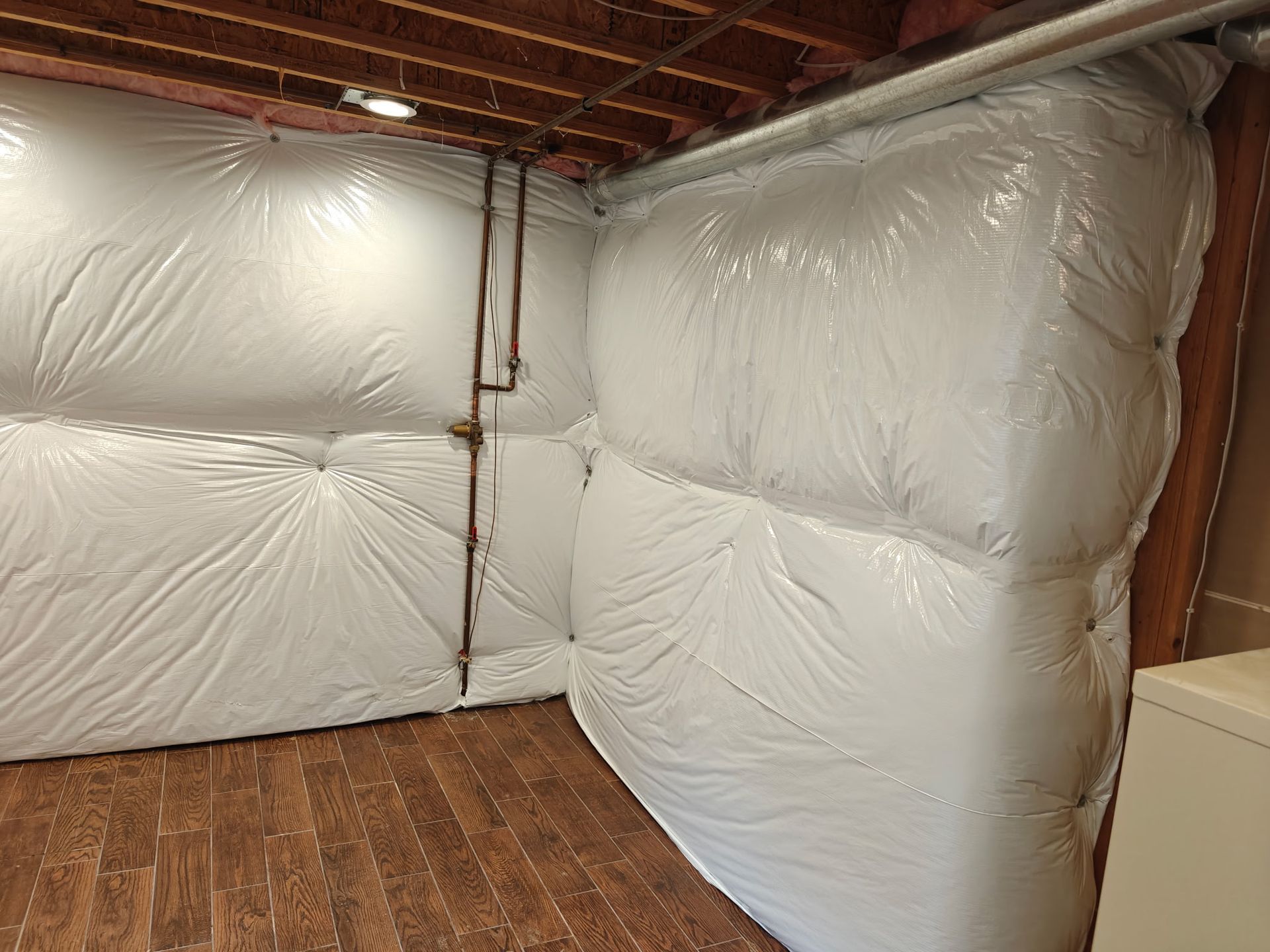 Old basement with concrete walls, stairs, and cracked floor. One wall has yellow insulation.