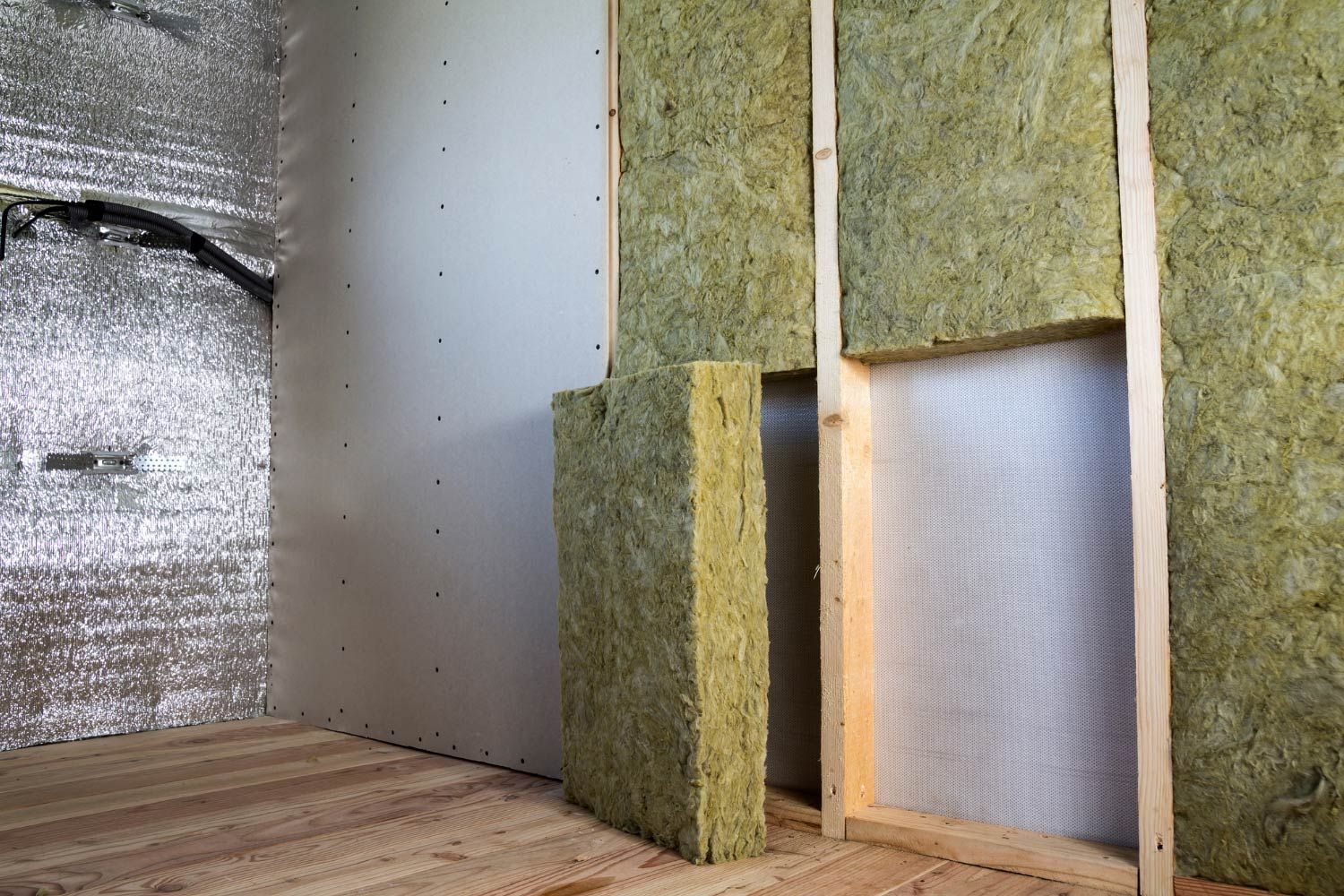 Interior wall construction: wood studs, insulation, foil-faced material, and drywall.