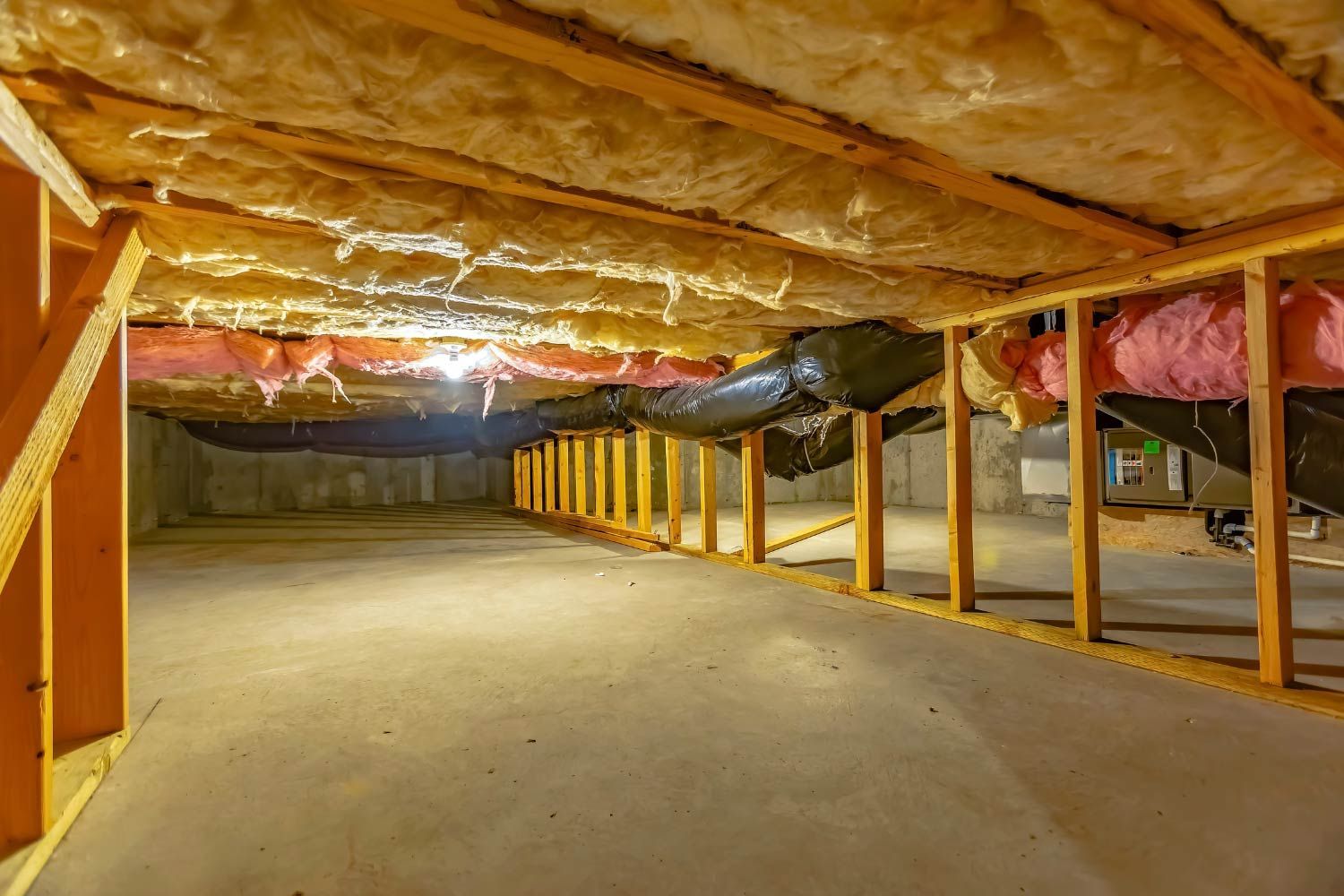 Person spraying insulation into a wall cavity, wearing protective gear. Inside a partially constructed room.