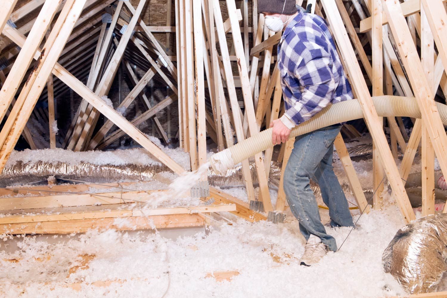Person in protective gear sprays foam insulation into a wall cavity.