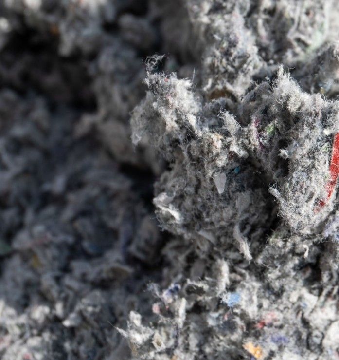 Gray, shredded cellulose insulation material, close-up, with flecks of color.