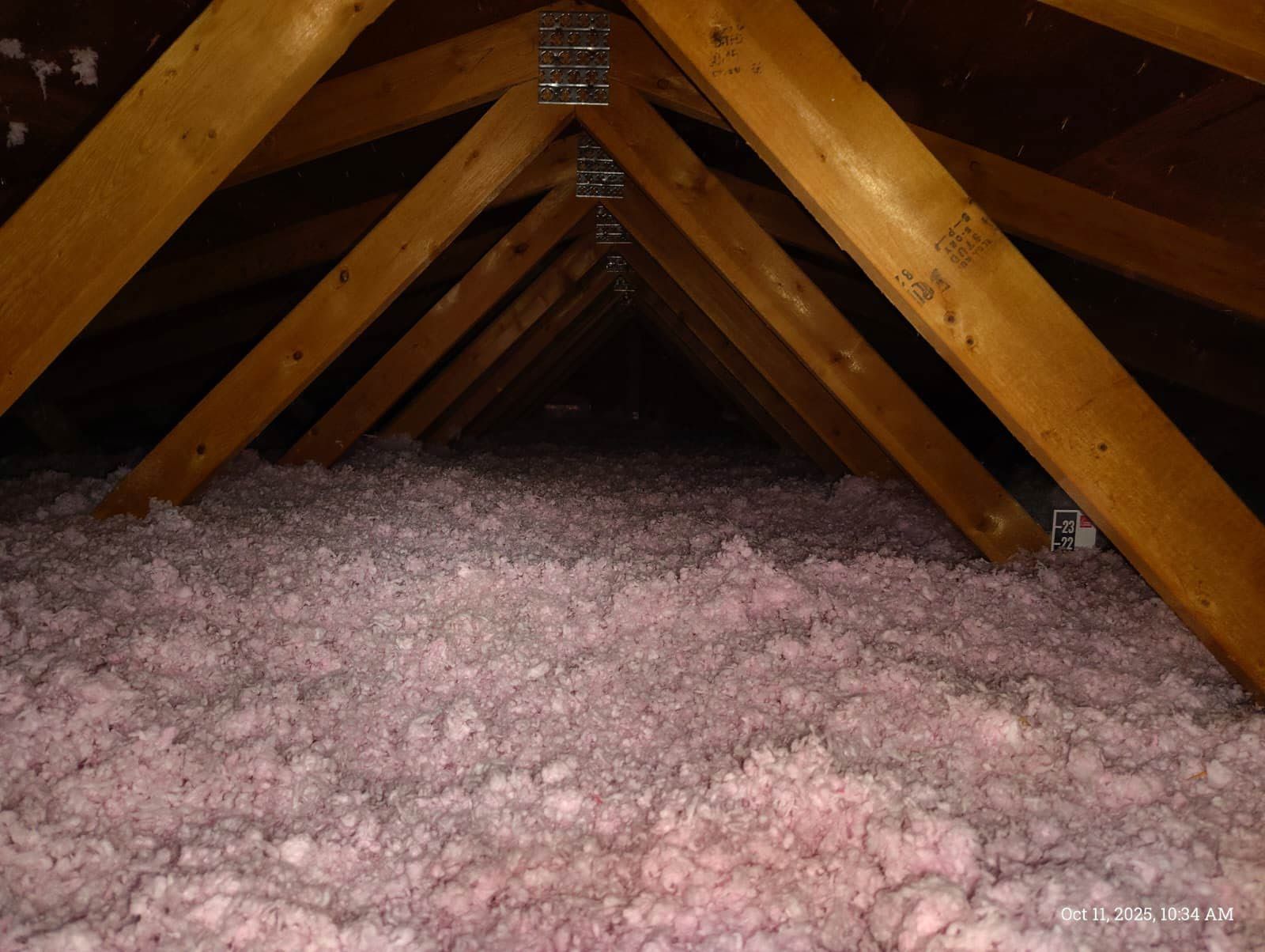Person kneeling, spraying foam insulation into a wooden wall.