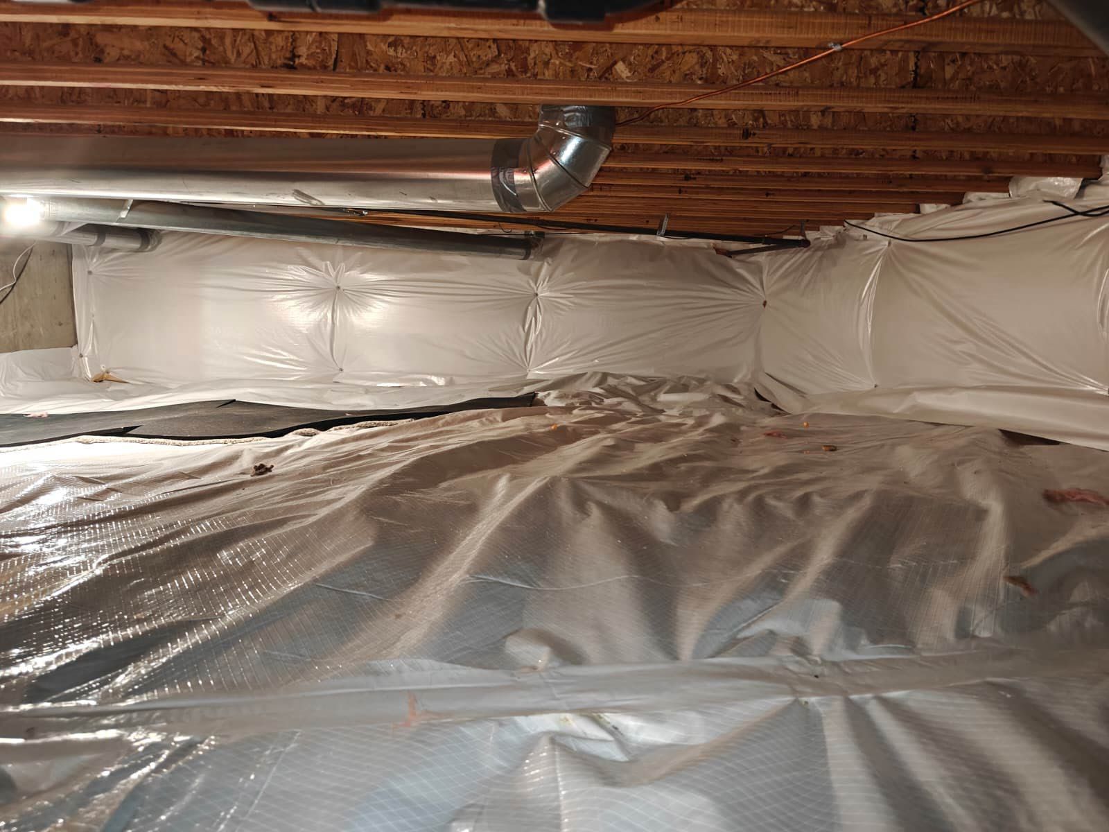 Person in protective suit spraying foam insulation into a wall cavity.