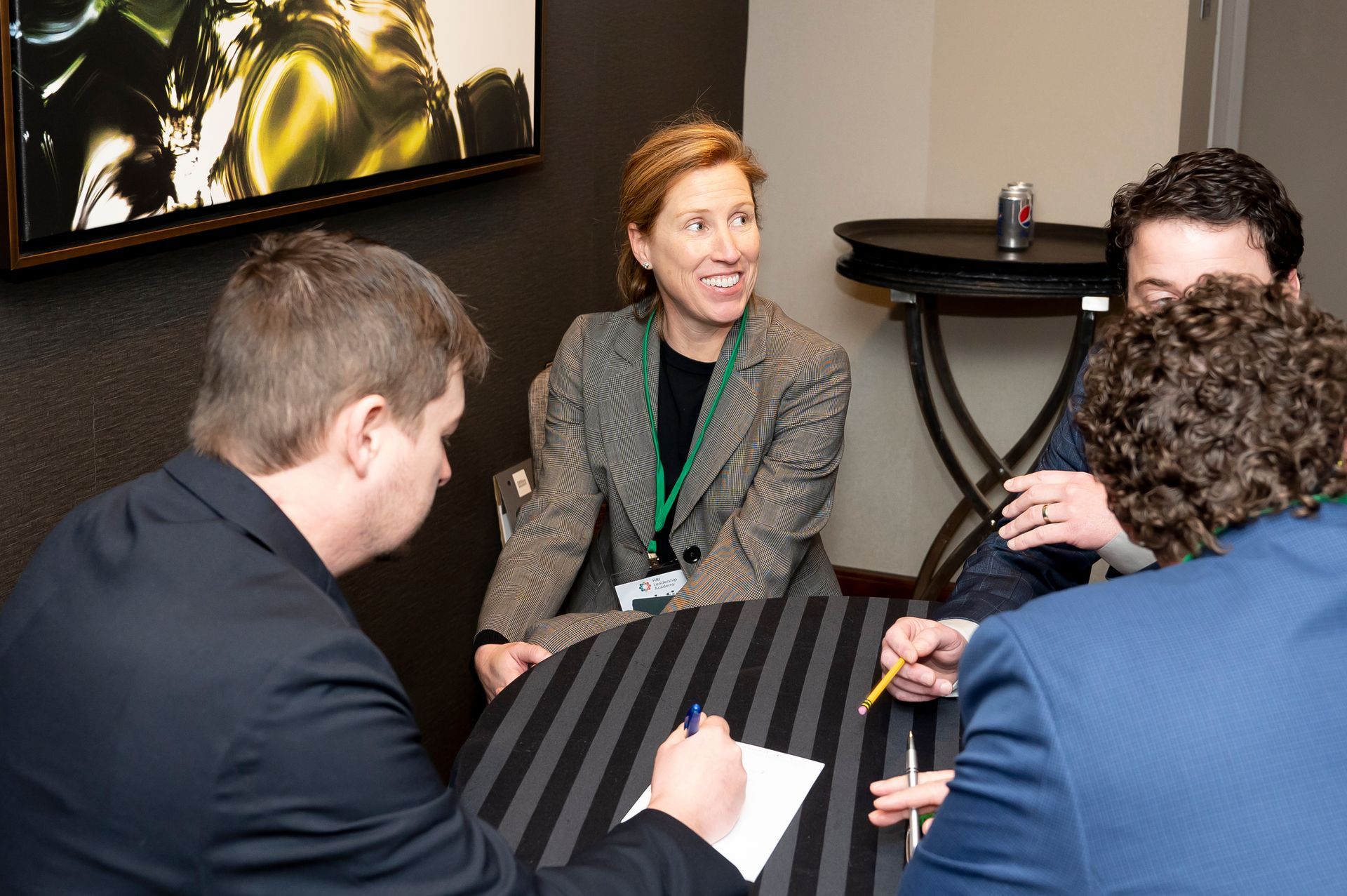 a group of people are sitting around a table having a conversation .