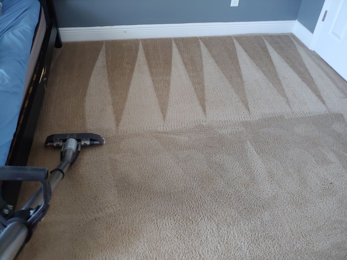 A vacuum cleaner is cleaning a carpet in a bedroom.