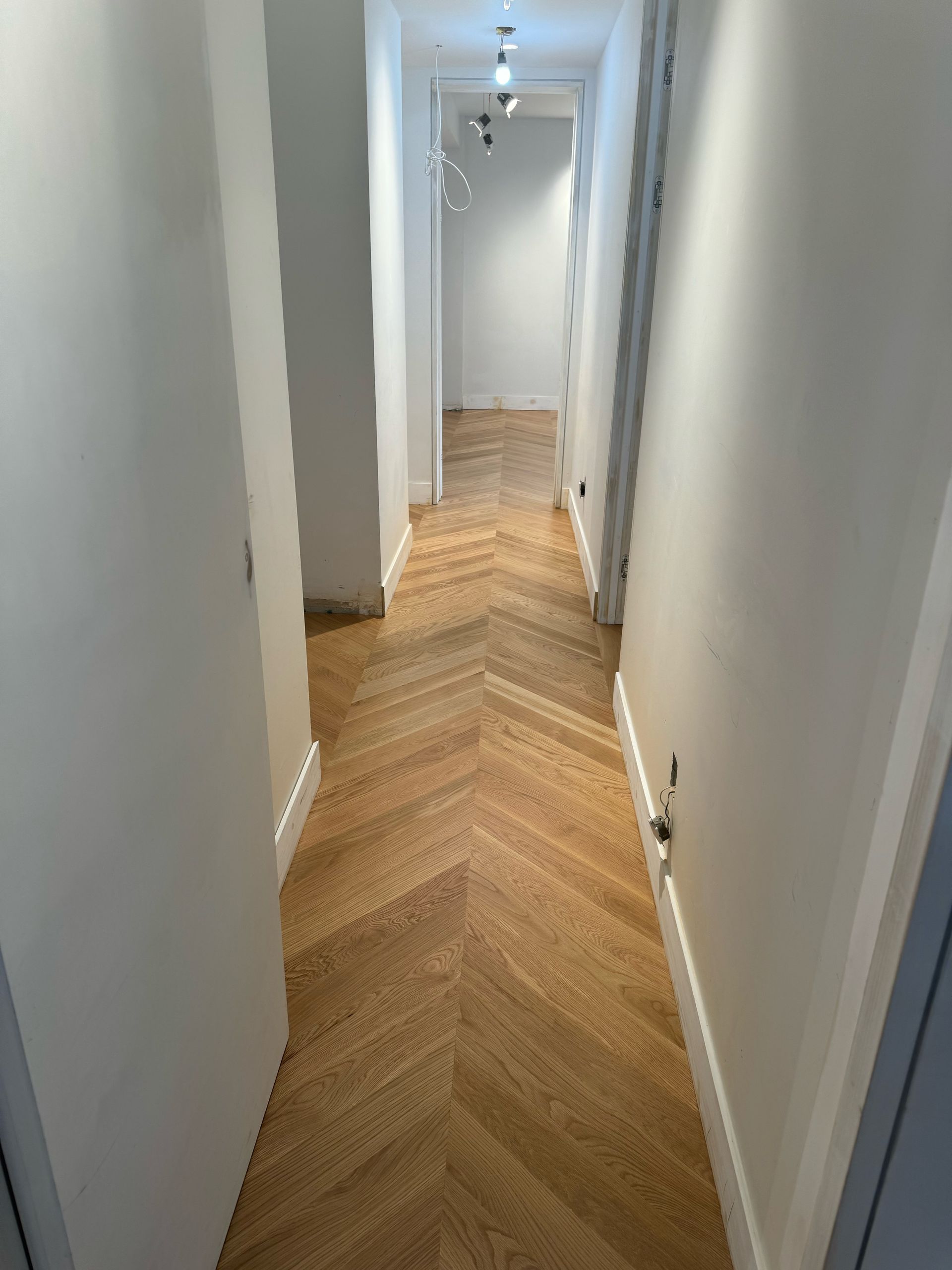 A long hallway with a wooden floor and white walls.