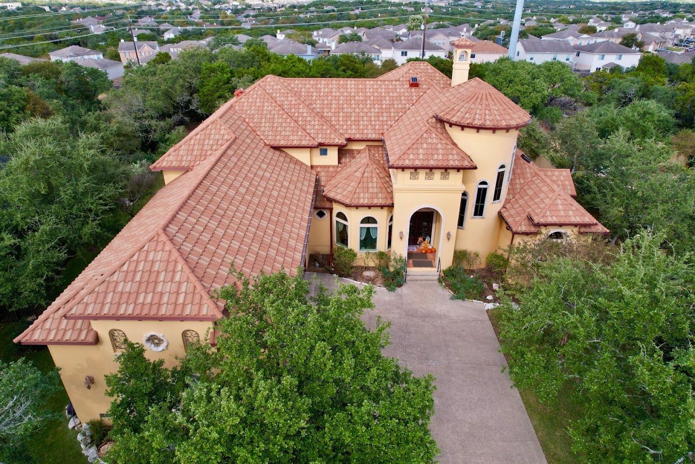 An aerial view of a large house with a tiled roof surrounded by trees.