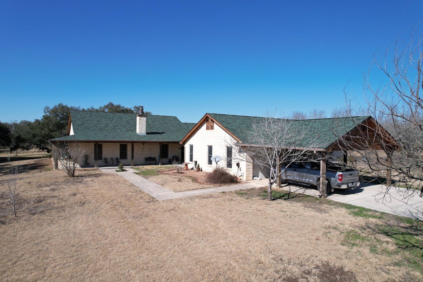 A large white house with a green roof and a truck parked in front of it.