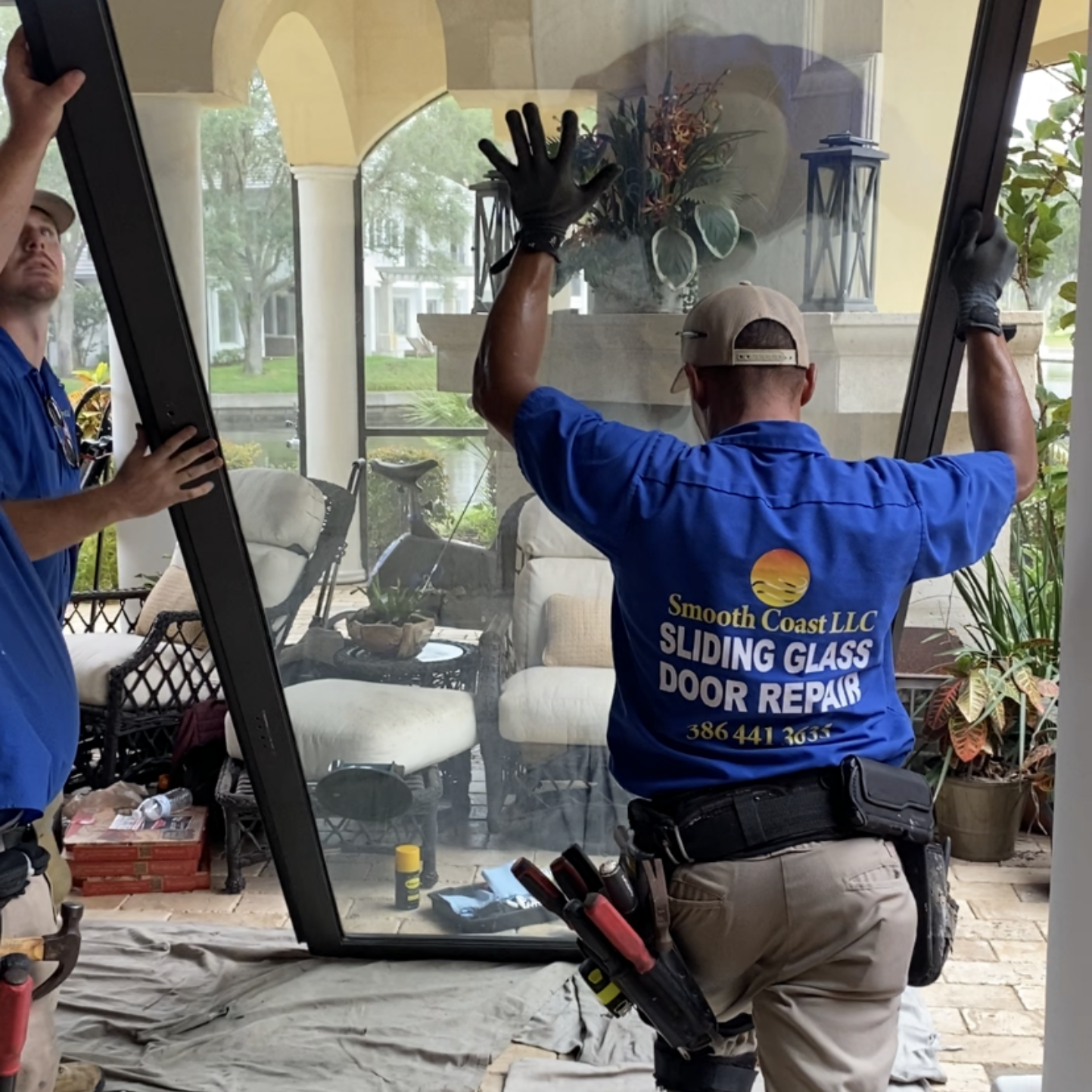 Two men lifting a large glass pane to install it. Two men lifting a large glass pane to install it.