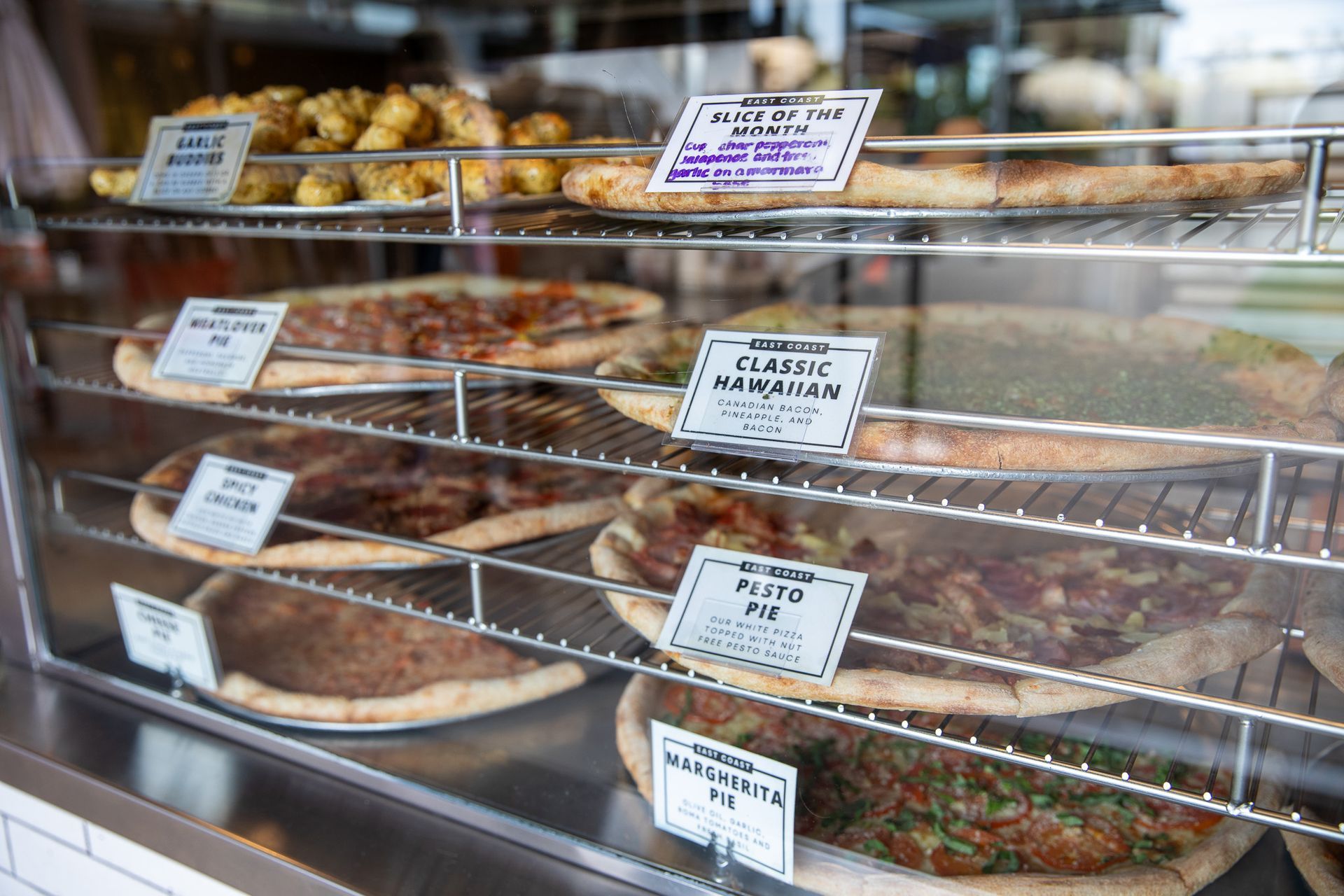 Display case filled with various savory pies and pastries, each labeled with a sign.