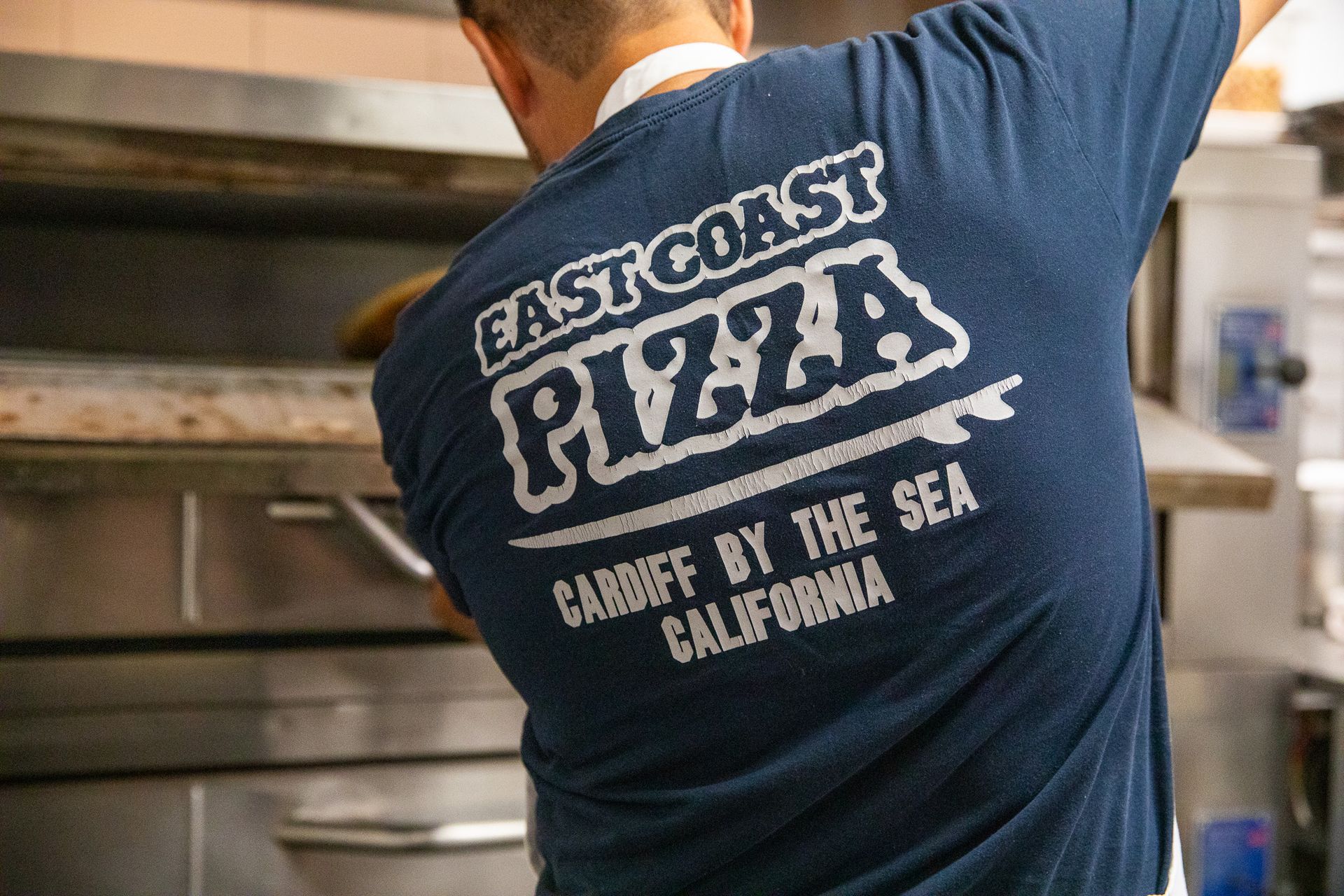 The logo for east coast pizza shows a slice of pizza