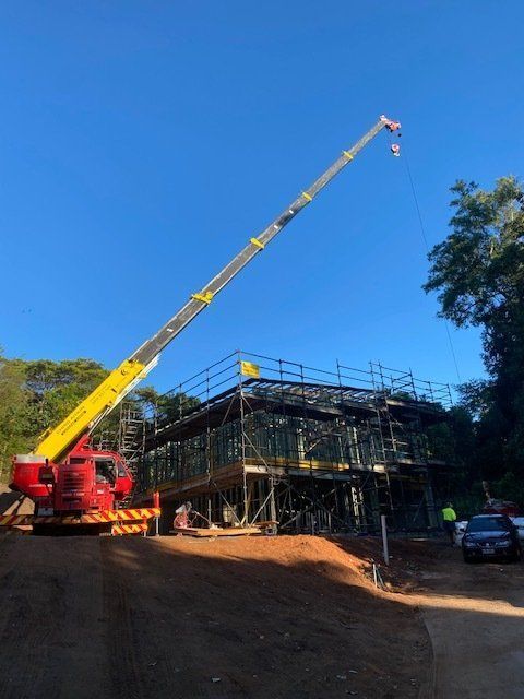 A Red and Yellow Crane is Sitting in Front of a Building Under Construction — CA Crane Hire in Forest Glen, QLD
