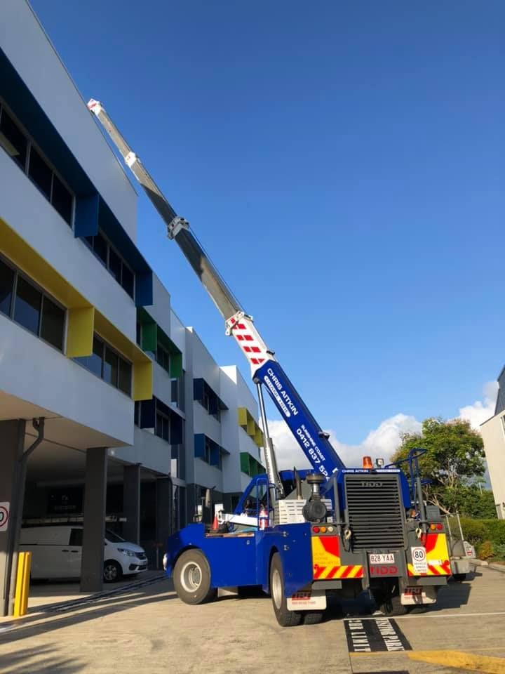 A Blue Crane is Parked in Front of a Building — CA Crane Hire in Maroochydore, QLD