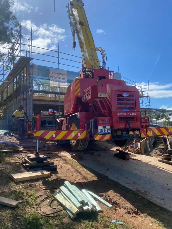 A Red Crane is Parked in Front of a Building Under Construction — CA Crane Hire in Caloundra, QLD