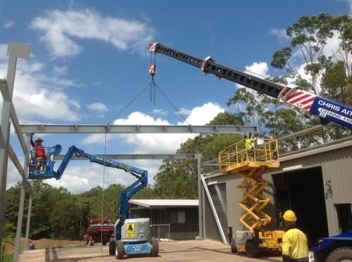 A Crane is Lifting a Metal Structure in Front of a Building — CA Crane Hire in Maroochydore, QLD