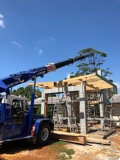 A Blue Truck With a Crane Attached to It is Parked in Front of a Building — CA Crane Hire in Forest Glen, QLD