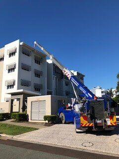 A Blue Truck With a Crane Attached to It is Parked in Front of a Building — CA Crane Hire in Forest Glen, QLD