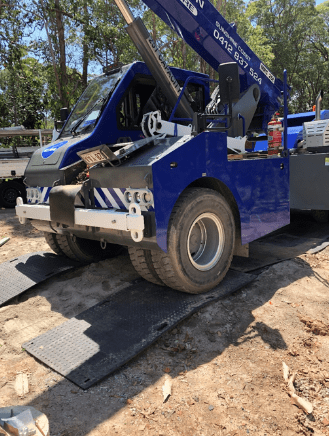 A Blue Tow Truck is Parked on a Rubber Mat in the Dirt — CA Crane Hire in Forest Glen, QLD