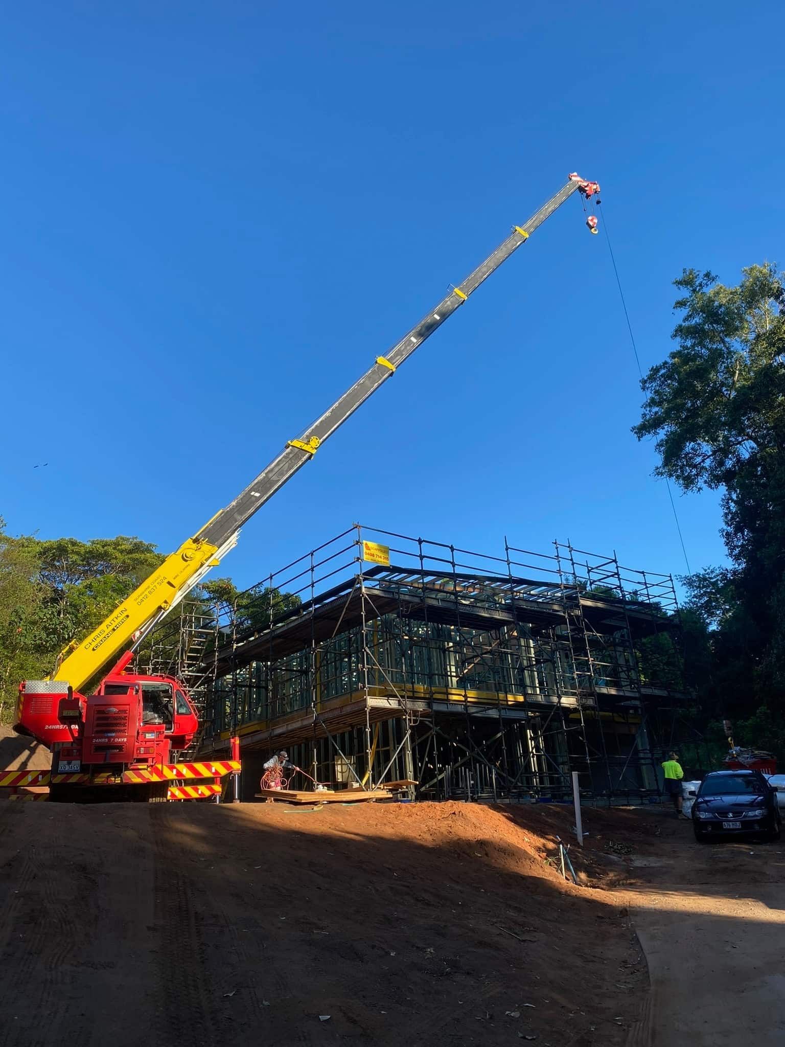 A Large Crane Is Sitting In Front Of A Building Under Construction — CA Crane Hire in Forest Glen, QLD