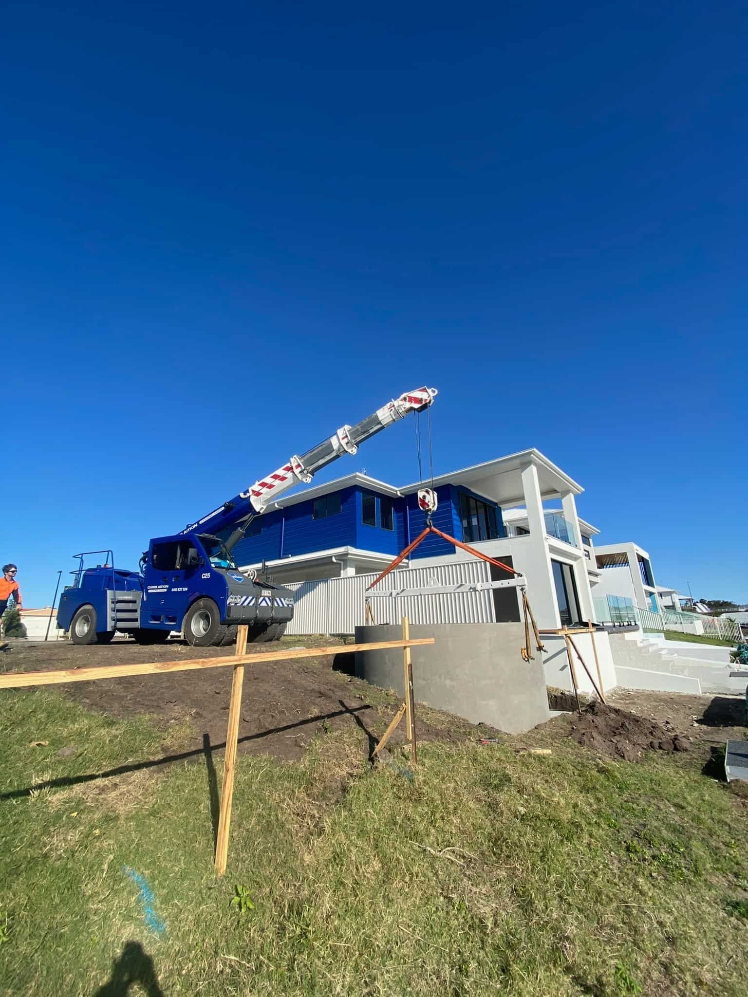 A Blue Truck With A Crane Attached To It Is Parked In Front Of A House Under Construction — CA Crane Hire in Forest Glen, QLD