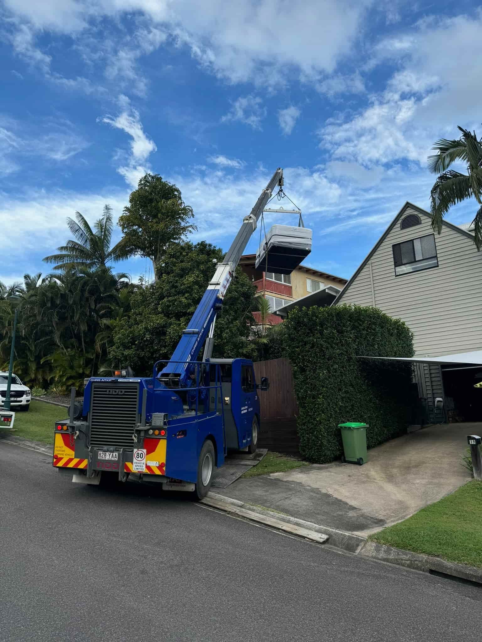A Blue Truck With A Crane Attached To It Is Parked In Front Of A House Under Construction — CA Crane Hire in Forest Glen, QLD