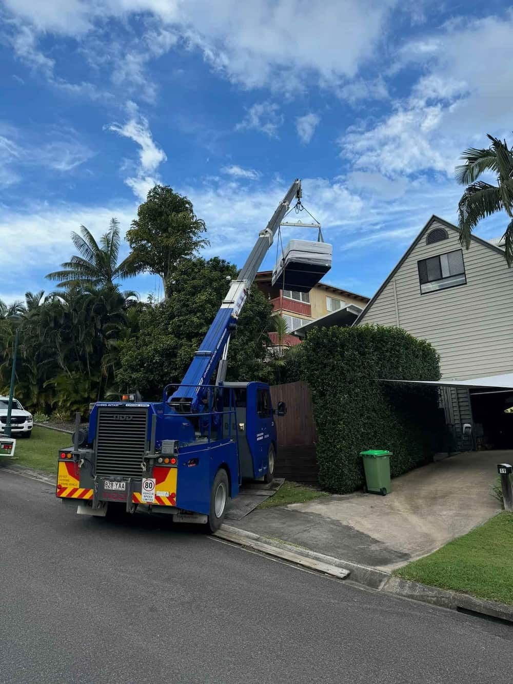 A Blue Truck With A Crane Attached To It Is Parked In Front Of A House  — CA Crane Hire in Forest Glen, QLD