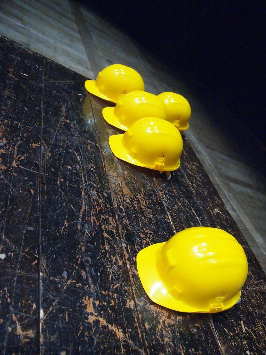 Four Yellow Hard Hats Are Lined Up on a Wooden Table — CA Crane Hire in Forest Glen, QLD