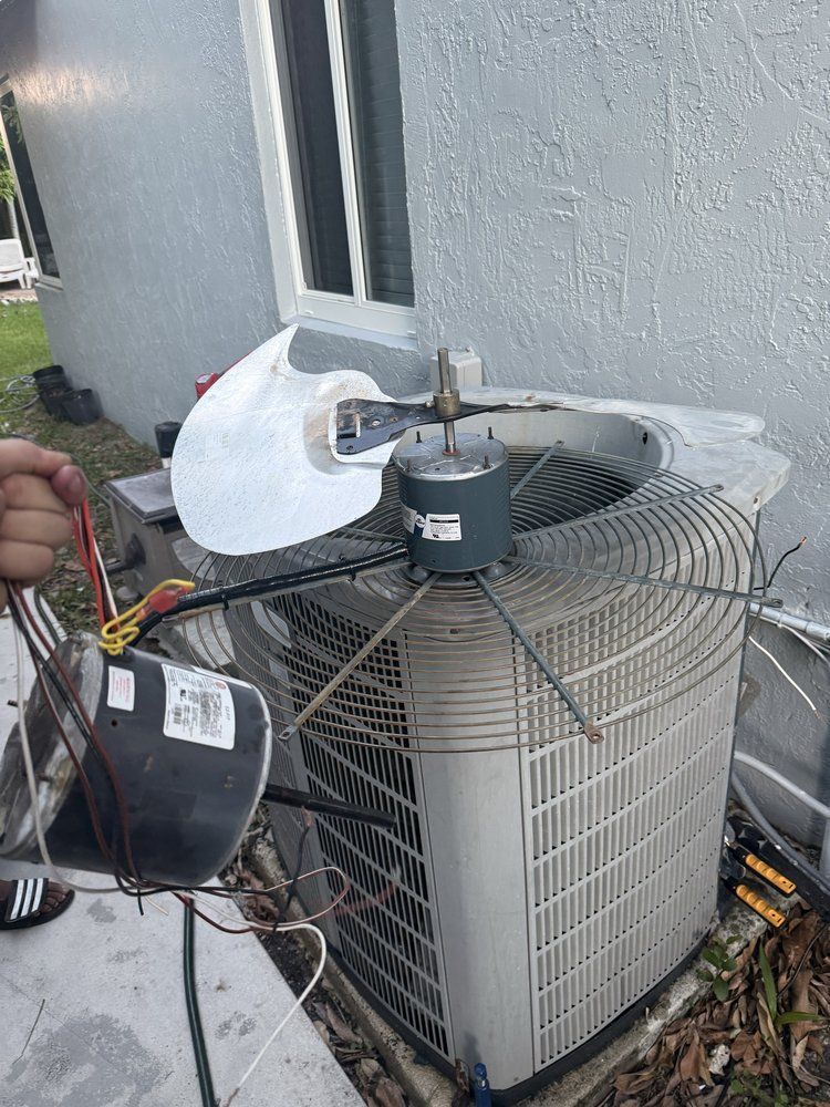 Air conditioning unit with removed fan and electrical components being held.