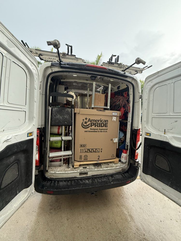 Open white cargo van's back doors, revealing interior filled with tools and a large American Pride box.