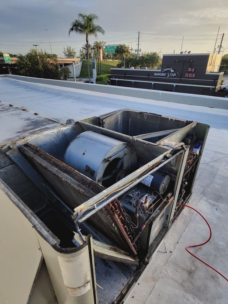 Opened rooftop HVAC unit with a large fan and cooling coils.