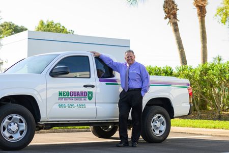 A man in a purple shirt and tie is standing next to a white truck.
