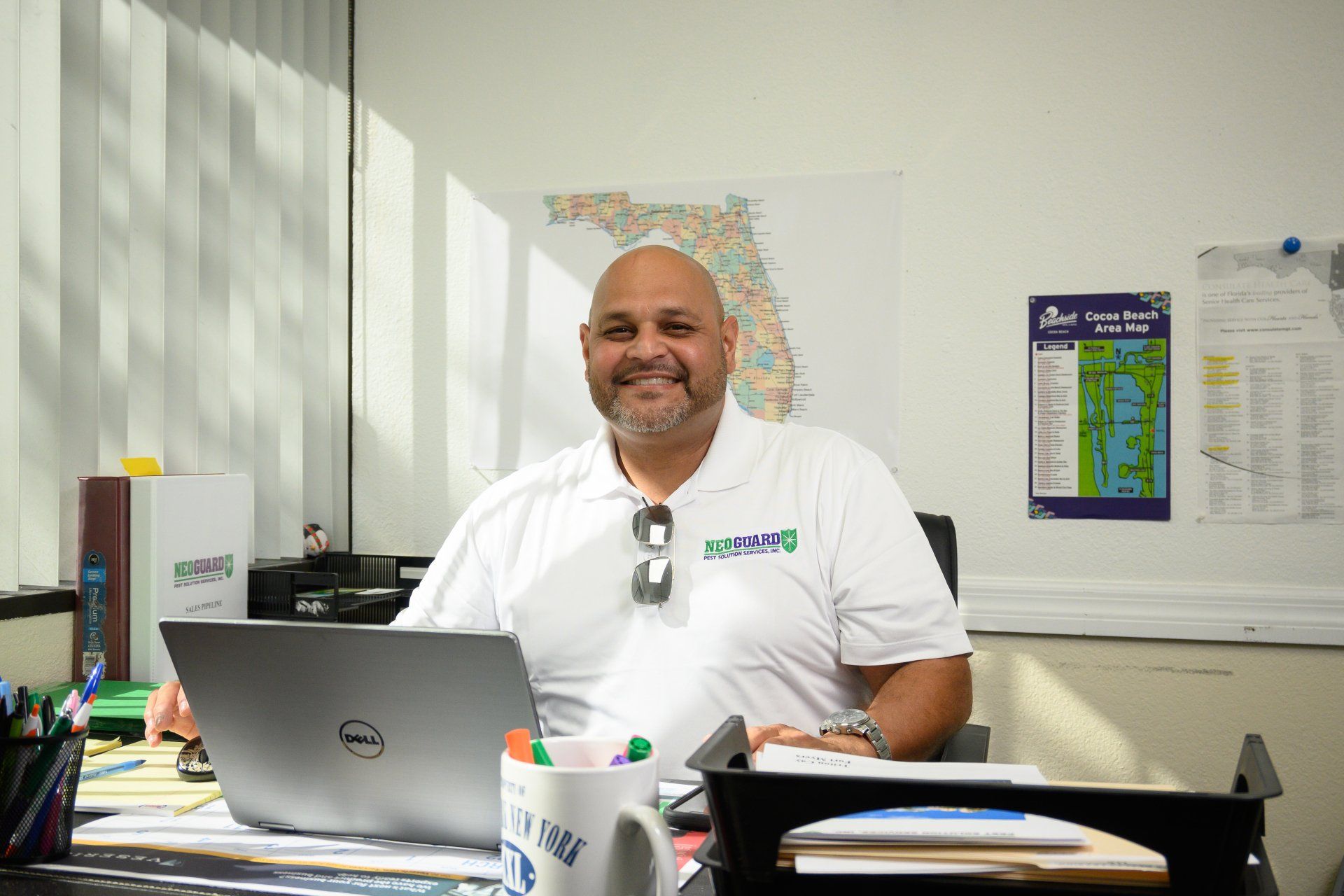 A man is sitting at a desk in front of a laptop computer.