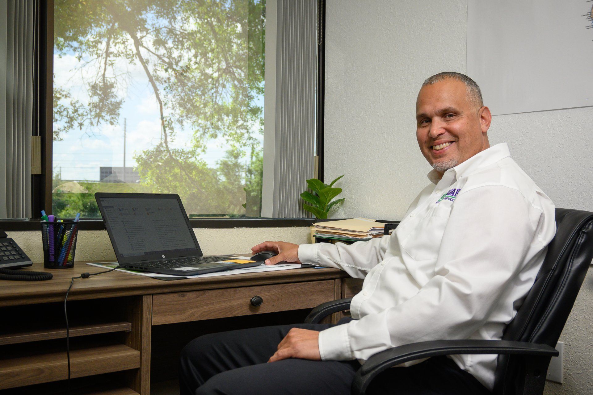 A man is sitting at a desk in front of a laptop computer.