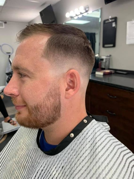 A man with a beard is getting his hair cut at a barber shop.