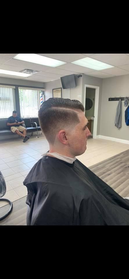 A man is getting his hair cut at a barber shop.