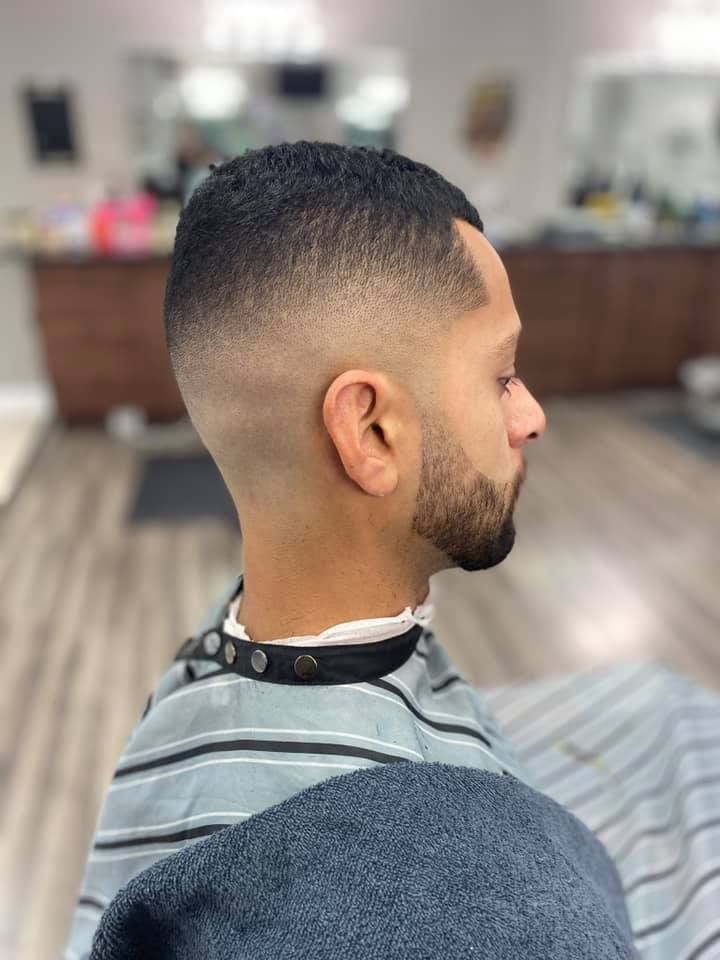 A man with a beard is getting his hair cut at a barber shop.