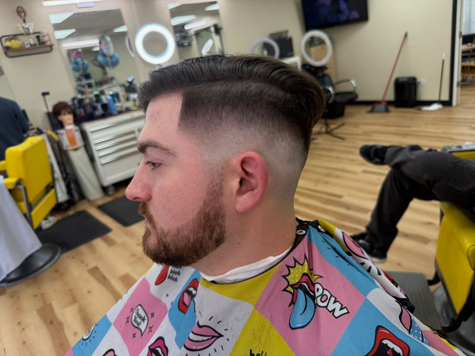 A man is getting his hair cut at a barber shop.