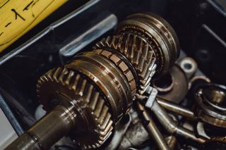 A greasy automotive transmission gear assembly sitting in a storage bin.