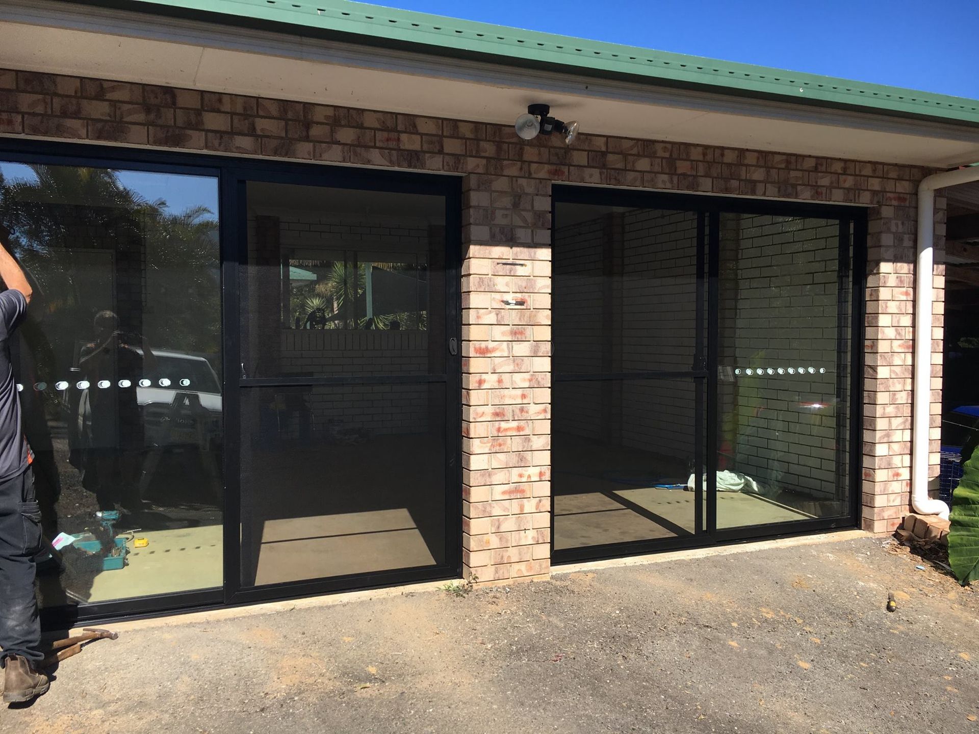 Two Black-framed Sliding Glass Doors With Screen Doors in Brick Building — Datco Windows & Doors Pty Ltd In South Murwillumbah, NSW