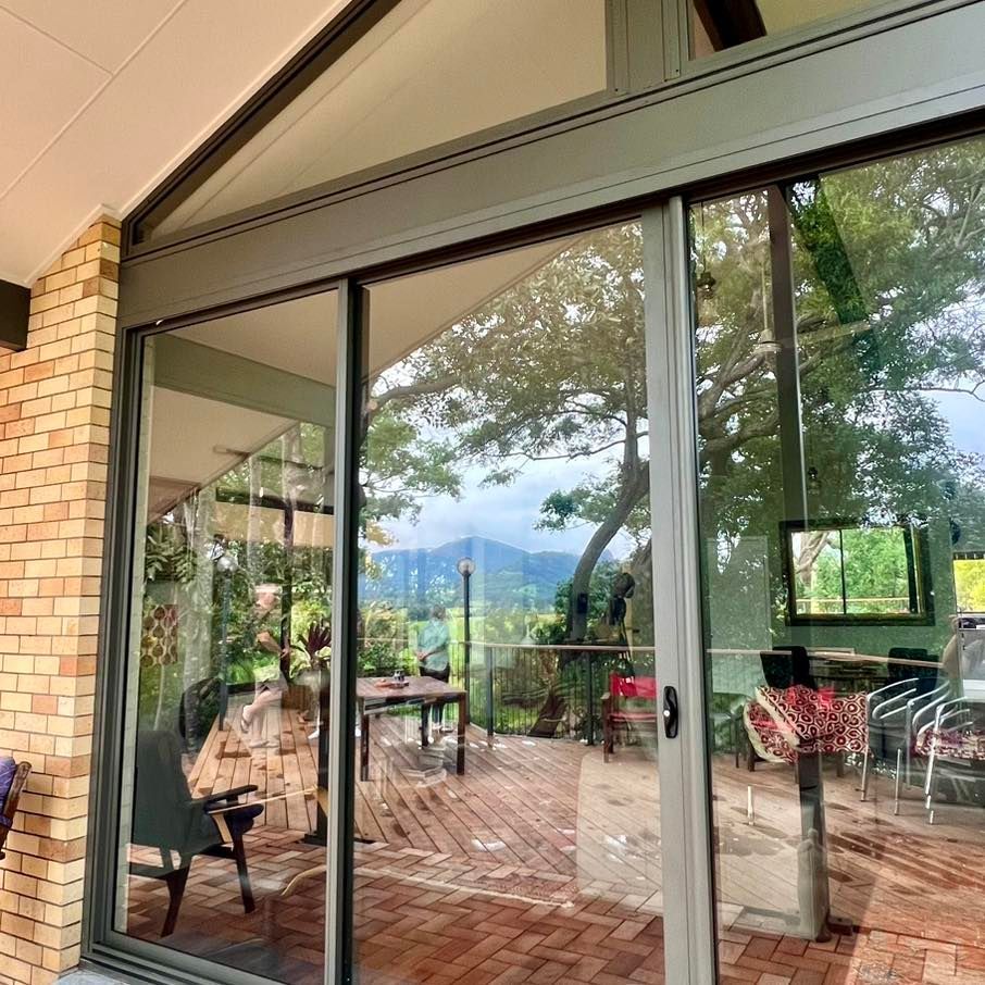 A Large Window With a Reflection of a Person in It — Datco Windows & Doors Pty Ltd In South Murwillumbah, NSW