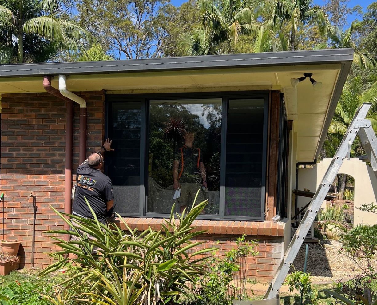 Two Workers Installing Large Windows in a Brick Building — Datco Windows & Doors Pty Ltd In South Murwillumbah, NSW