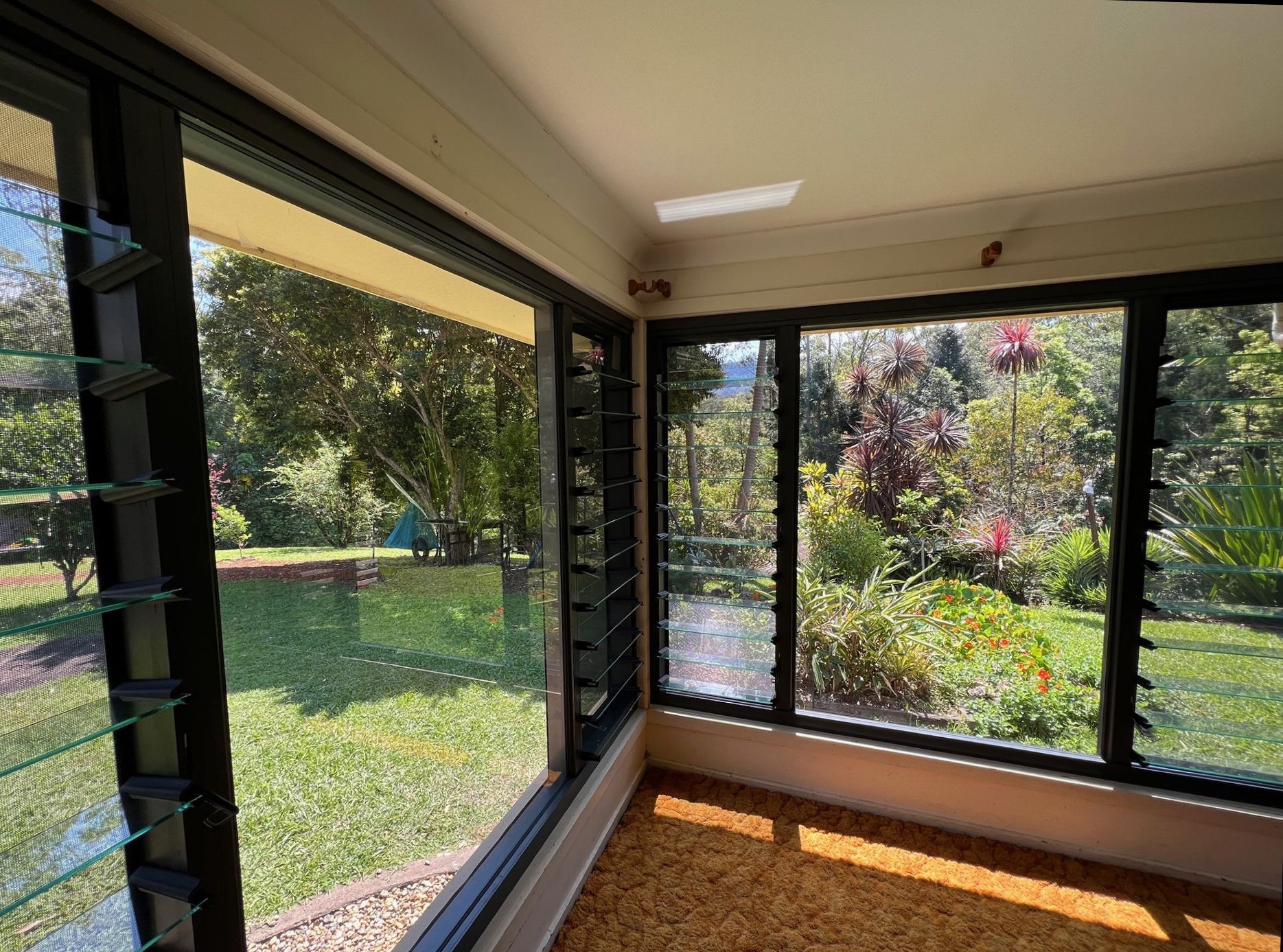 Sunroom With Black-framed Windows Overlooking a Lush Green Garden and Lawn — Datco Windows & Doors Pty Ltd In South Murwillumbah, NSW