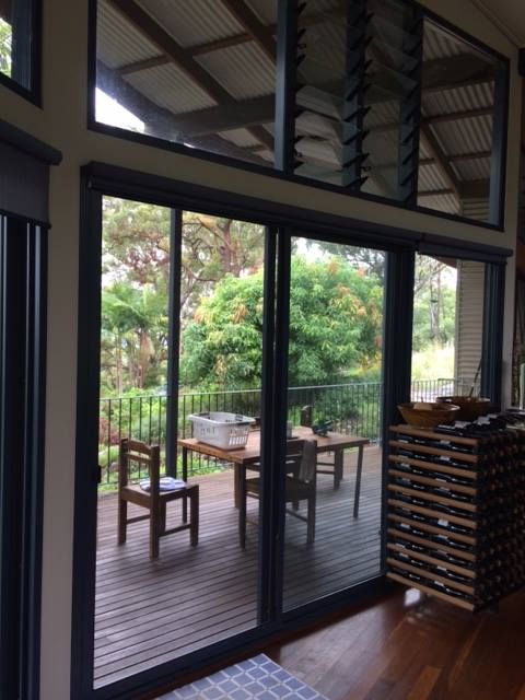 Sliding Glass Doors Open Onto a Deck With a Table and Chairs — Datco Windows & Doors Pty Ltd In South Murwillumbah, NSW