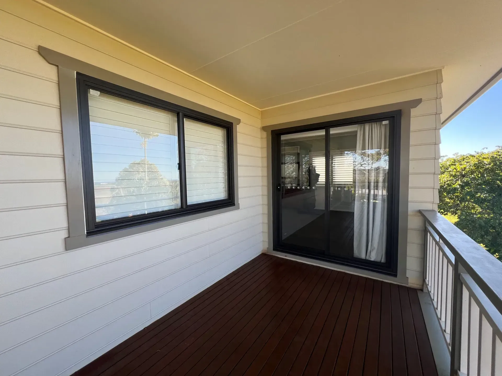 Balcony With Dark Wood Decking, White Siding, Black-framed Windows/door, and Metal Railing — Datco Windows & Doors Pty Ltd In South Murwillumbah, NSW